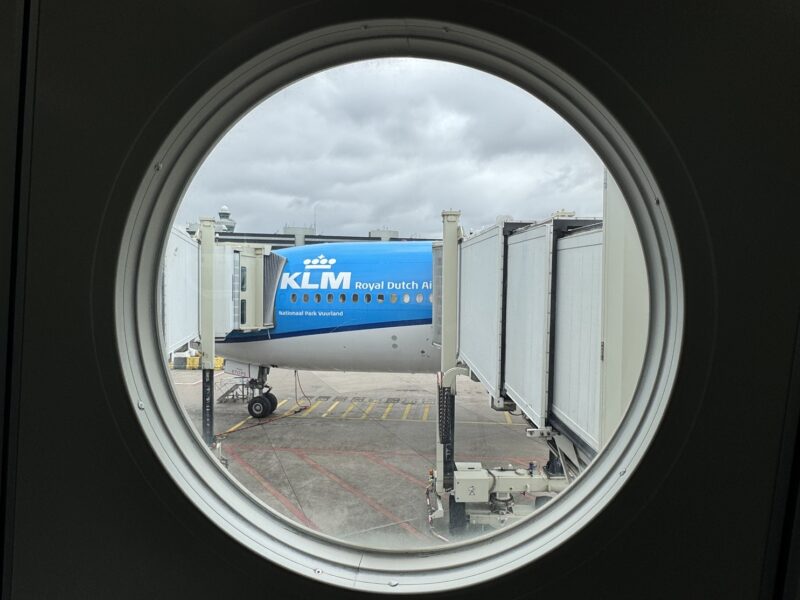 Un Boeing 777-300ER de KLM vu à travers le hublot d'une passerelle à l'aéroport d'Amsterdam-Schiphol