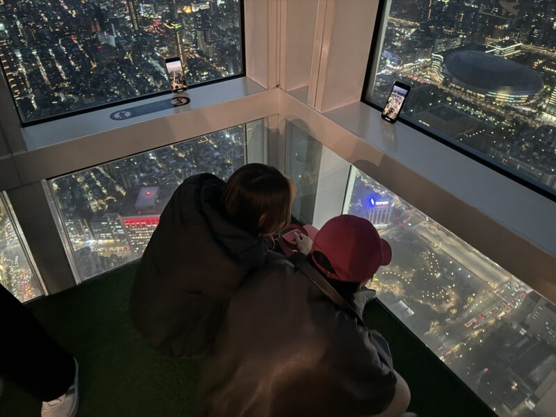 Des jeunes gens filment le coucher de soleil sur leur téléphone, en haut de l'observatoire de la Taipei 101