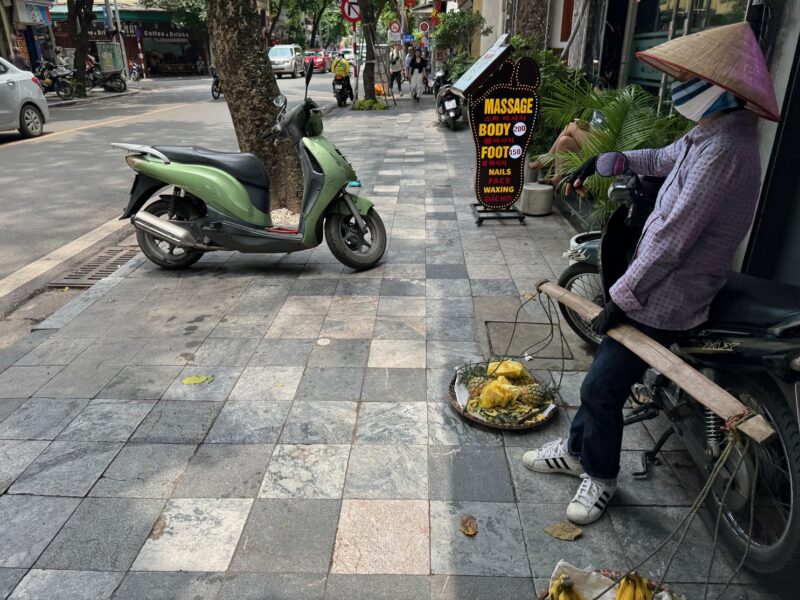 Un marchand ambulant à Hanoï (Vietnam) avec une palanche et un non toi (chapeau conique traditionnel)