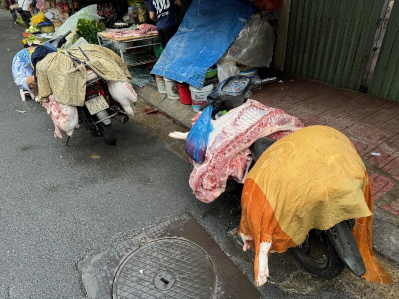 Des carcasses de porc chargées sur des scooters, dans un marché à Hanoï (Vietnam)