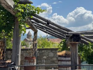 Vue sur la cathédrale de Svetitskhoveli entre les vignes qui recouvrent la pergola de cette maison à Mtskheta (Géorgie)