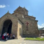 Vue sur l'entrée de la cathédrale de Svetitskhoveli à Mtskheta (Géorgie), avec au loin à droite le monastère de Jvari