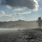 La vue sur des marcheurs sur la Playa Venao, au sud de la péninsule d'Azuero (Panama), alors que la plage est recouverte par l'écume de l'océan Pacifique