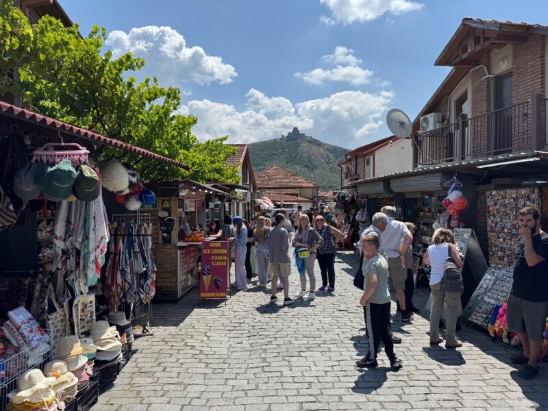 Vue sur une ruelle touristique de Mtskheta, l'ancienne capitale de Géorgie, avec le monastère de Jvari en arrière-plan sur la colline