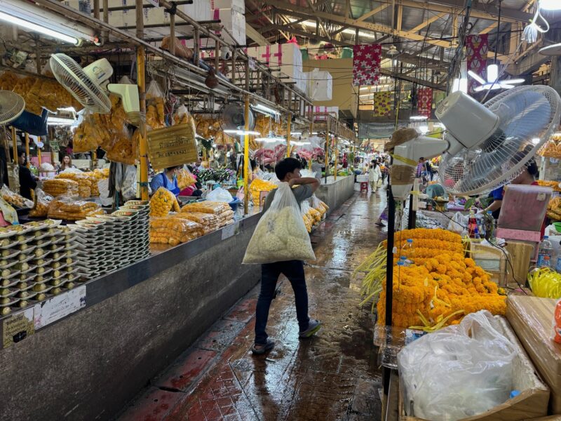 Un marchand de fleurs dans les allées du marché de Pak Khlong Talat à Bangkok (Thaïlande)
