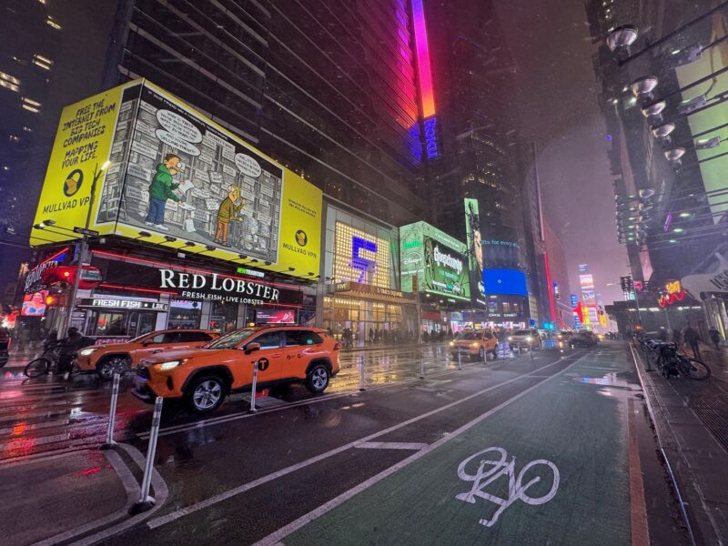 Des taxis jaunes arrêtés à l'angle de la 41e rue et de la 7e avenue, avec les lumières de Times Square en arrière-plan