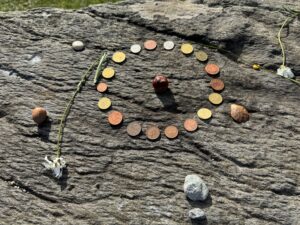 Des pièces de monnaie (euros, livres sterling) posées en cercle sur la pierre plate qui forme l'autel du cromlech de Drombeg