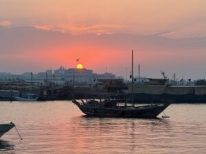 Vue sur le coucher du soleil, derrière le palais princier du Qatar avec un Shu'i (bateau traditionnel) au premier plan